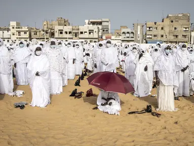 Pengikut komunitas Layene Senegal terlihat selama perayaan Tabaski (Idul Adha) di lingkungan populer Yoff di Dakar, Rabu (21/7/2021). Para jemaah mengenakan pakaian putih untuk merayakan hari raya umat Muslim yang dikenal di Senegal sebagai 'Tabaski'. (JOHN WESSELS / AFP)