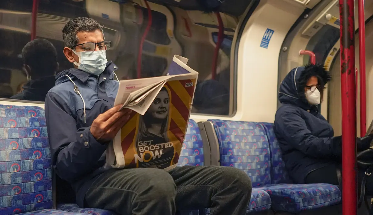 Seorang pria memakai masker saat membaca koran di kereta bawah tanah London, di London, Kamis (16/12/2021). Inggris mencatat jumlah tertinggi infeksi COVID-19 baru yang dikonfirmasi pada hari Rabu (15/12) sejak pandemi dimulai. (AP Photo/Alberto Pezzali)