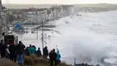 Sejumlah warga berkumpul menyaksikan debur ombak yang disebabkan badai Eleanor di pinggir laut Wimereux, utara Prancis (3/1). Badai Eleanor memaksa penghentian layanan transportasi dan kereta api.  (AFP Photo/Francois Lopresti)