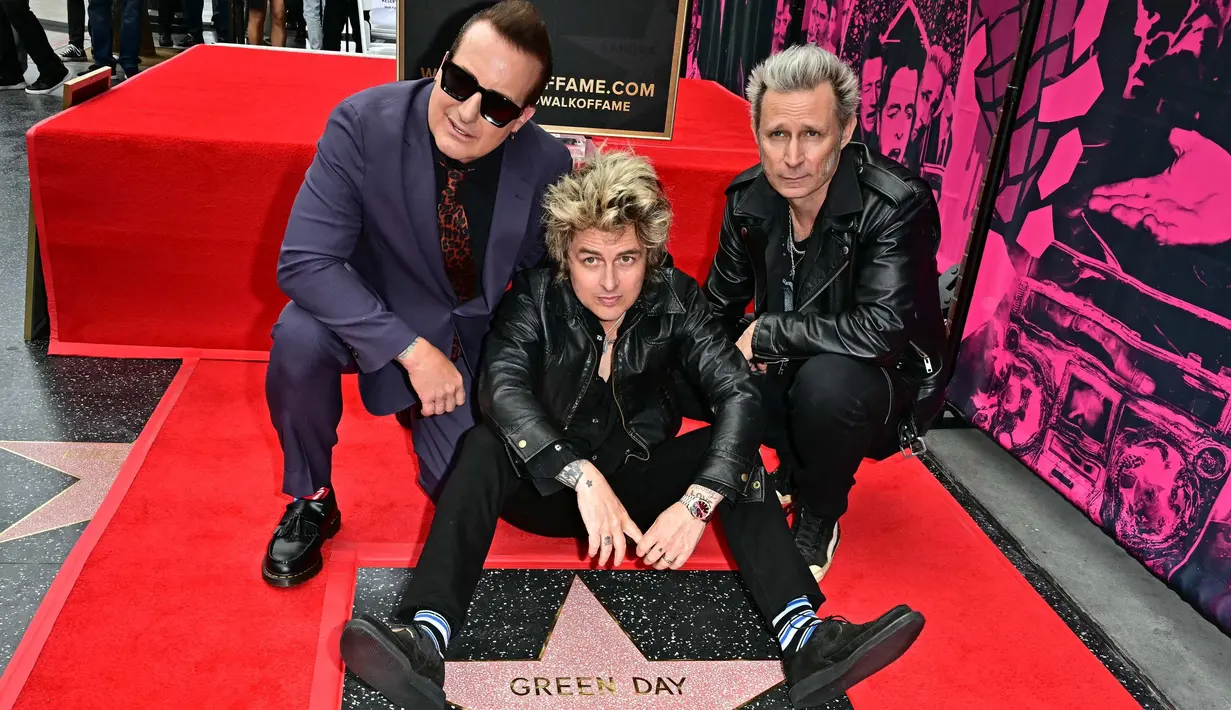 Personel grup band punk rock Green Day, Billie Joe Armstrong (tengah), Mike Dirnt (kanan), dan Tre Cool berpose dengan bintang mereka yang baru saja diresmikan di Hollywood Walk of Fame dalam sebuah upacara di Hollywood, California, Amerika Serikat pada 1 Mei 2025. (Frederic J. Brown/AFP)
