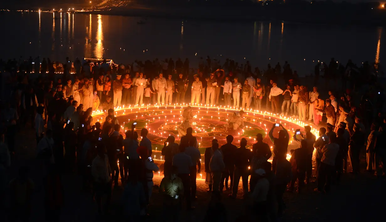 Polisi India menyalakan lilin di Sangam saat festival 'Dev Deepawali,' atau festival cahaya, di Allahabad, Rabu (25/11).  Festival ini adalah perayaan atas kemenangan kebaikan atas kejahatan. (AFP PHOTO/Sanjay Kanojia)