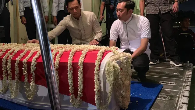 Dua putra Ani Yudhoyono, Agus Harimurti Yudhoyono dan Edhie Baskoro Yudhoyono, memegang peti jenazah dan mendampinginya saat masuk ke pesawat.