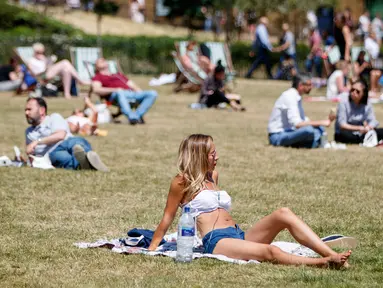 Sejumlah warga Inggris bersantai di atas rumput sambil menikmati sinar matahari di Green Park, London, Senin (25/6). Pada Juli 2018, suhu di ibu kota London tercatat 29.1 derajat Celcius dan diprediksi akan mencapai 30 derajat Celcius. (AFP/Tolga Akmen)