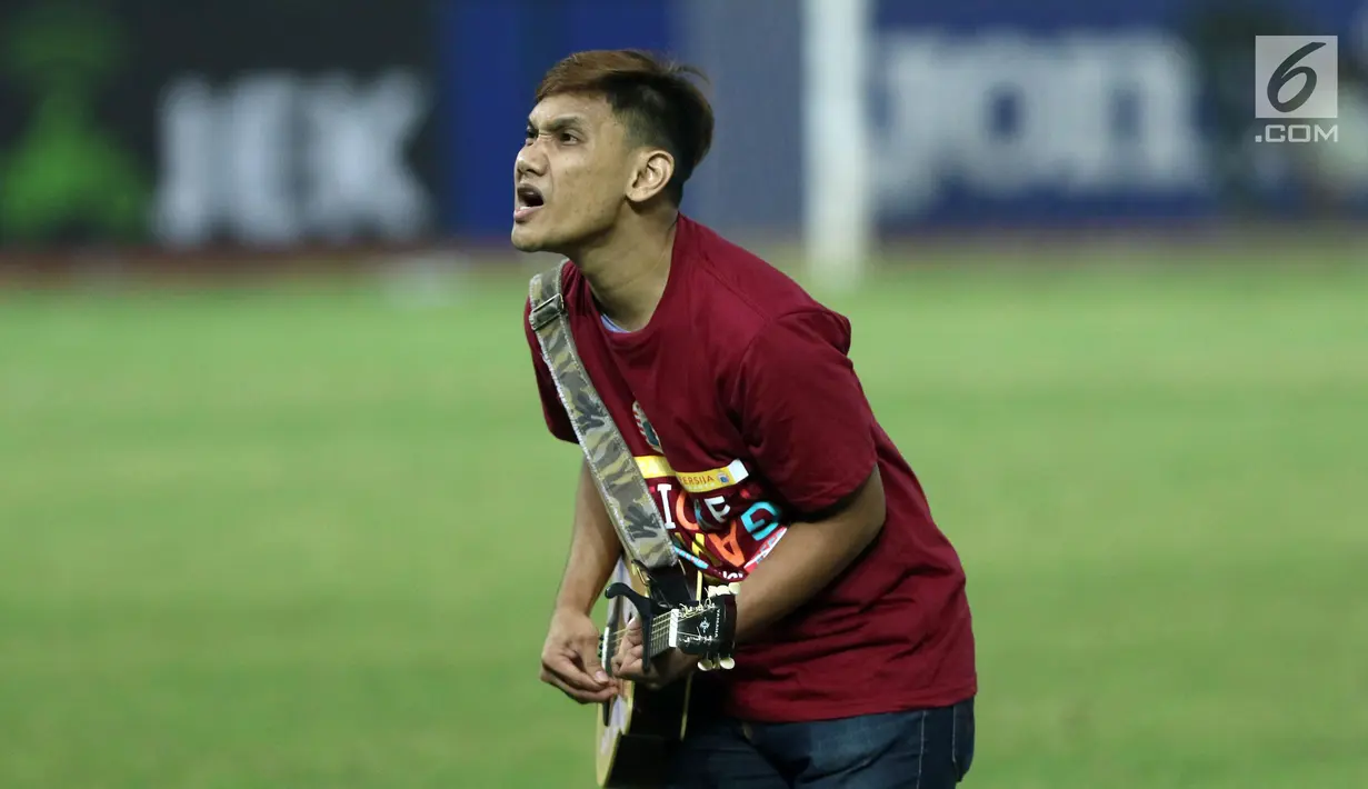 Salah satu suporter memainkan gitar akustik mengiringi nyanyian pendukung tim Macan Kemayoran usai menyaksikan laga Persija melawan Persipura di Stadion Patriot Candra Bhaga, Bekasi, Sabtu (8/7). (Liputan6.com/Helmi Fithriansyah)