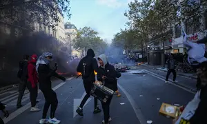 Sejumlah demonstran berdiri di depan sepeda yang terbakar saat aksi menentang kenaikan biaya hidup sekaligus menyuarakan tuntutan mahasiswa di Paris, Prancis, Sabtu (17/10/2026). (AP Photo/Thibault Camus)