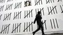 Seorang pria berjalan di sebelah tembok besar yang dimural oleh seniman Banksy di wilayah Manhattan, New York (15/3). Di bagian ujung mural tersebut, Banksy menuliskan pesan "Free Zehra Dogan". (Spencer Platt / Getty Images / AFP)