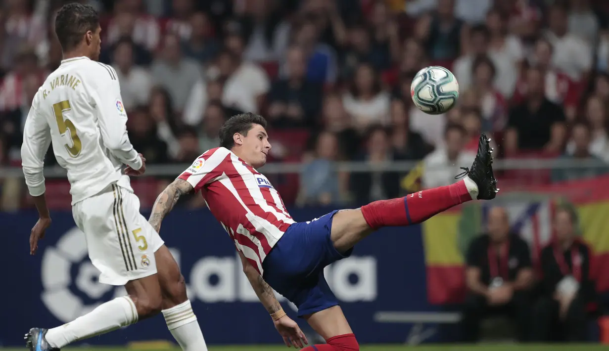 Pemain Atletico Madrid, Jose Gimenez berusaha mengontrol bola dari kawalan bek Real Madrid, Raphael Varane  selama pertandingan lanjutan La Liga di stadion Wanda Metropolitano, Spanyol (28/9/2019). Madrid dan Atletico bermain imbang 0-0. (AP Photo/Bernat Armangue)