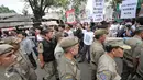 Satpol PP melintas di dekat warga yang menggelar aksi damai di tengah penggusuran kawasan Bukit Duri, Jakarta, Rabu (28/9). Pemprov DKI akhirnya melakukan penertiban pemukiman di Bukit Duri terkait revitalisasi sungai Ciliwung. (Liputan6.com/Yoppy Renato)