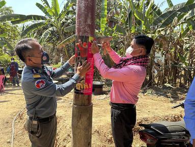 Dalam foto yang dirilis oleh Kementerian Kesehatan Kamboja ini, seorang petugas kesehatan hewan Kamboja, kanan, dan seorang perwira polisi militer memasang poster tentang kesadaran akan ancaman virus H5N1 dengan harapan dapat mengedukasi penduduk desa untuk menjaga kesehatan mereka, di Prey Veng, Kamis (23/2/2023). Seorang anak perempuan berusia 11 tahun di Kamboja meninggal karena flu burung dalam infeksi H5N1 manusia pertama yang diketahui di negara itu sejak 2014, kata pejabat kesehatan. (Cambodia Ministry of Health via AP)