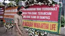 Warga berjalan dekat karangan bunga dari korban asuransi Jiwasraya yang terpajang di depan Gedung Pengadilan Tipikor, Jakarta, Rabu (3/6/2020). Puluhan karangan bunga tersebut berisi harapan para korban agar kasus segera tuntas dan uang mereka dapat kembali. (merdeka.com/Iqbal S. Nugroho)