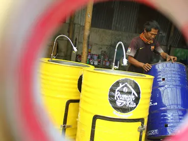 Perajin memproduksi wastafel portabel berbahan baku drum di workshop Galuh Creatives, Tangerang Selatan, Sabtu (30/5/2020). Wacana pemerintah menerapkan tatanan normal baru berimbas pada meningkatnya pesanan wastafel portabel untuk kebutuhan masyarakat di wilayah Jabotabek. (merdeka.com/Arie Basuki)