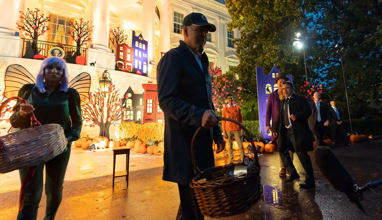Presiden Amerika Serikat Joe Biden (tengah) bersama Ibu Negara Jill Biden (kiri) berjalan untuk memberikan suguhan kepada wartawan saat perayaan Halloween di South Lawn Gedung Putih, Washington, Amerika Serikat, 31 Oktober 2022. Halloween bertema "Trick-or-Treating in the President and First Lady's Neighborhood" itu tampak meriah dengan dekorasi rumah hantu di Gedung Putih. (AP Photo/Alex Brandon)