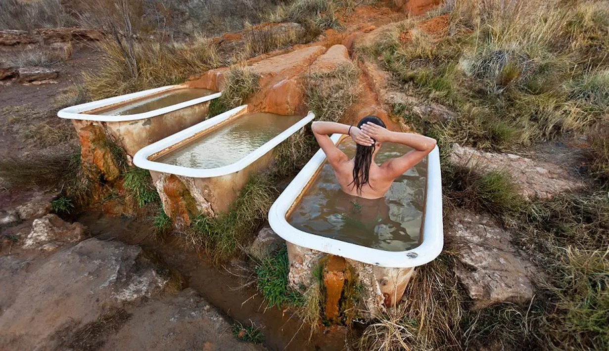 Seorang pengunjung saat menikmati bak mandi alami di Mystic Hot Springs di Utah, Amerika Serikat. Disini anda disuguhkan pengalaman mandi diatas bukit sambil menikmati Matahari terbenam dari atas. (Dailymail.co.uk)