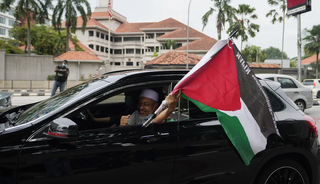 Warga Muslim membawa bendera Palestina saat konvoi protes menentang serangan Israel di Gaza di luar Kedutaan Besar Amerika Serikat di Kuala Lumpur, Malaysia, Jumat (21/5/2021).  (AP Photo / Vincent Thian)