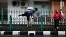 Seorang pria melompati pagar pembatas di Stasiun Cikini, Jakarta Pusat, Rabu, (20/12). Akses pintu keluar stasiun yang terlalu jauh membuat banyak penumpang yang mencari jalan pintas dengan melompat pagar satsiun. (Liputan6.com/Johan Tallo)