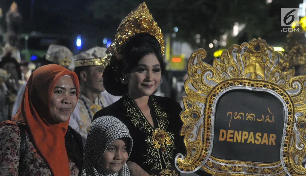 Warga berfoto dengan peserta yang menampilkan defile Denpasar pada pagelaran Semarang Night Carnival (SNC) 2019 di ruas Jalan Imam Bonjol, Rabu (3/7/2019). Parade festival kesenian dan budaya bertajuk Pelangi Nusantara tersebut diiikuti sebanyak 4.128 peserta. (Liputan6.com/Gholib)