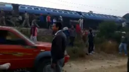 Sejumlah orang berkumpul di lokasi tergelincirnya kereta Indian Express di Negara Bagian Uttar Pradesh, India, Minggu (20/11). Sebagian besar korban berada di dua gerbong dekat mesin kereta, yang terbalik dan rusak parah. (ANI/via REUTERS)
