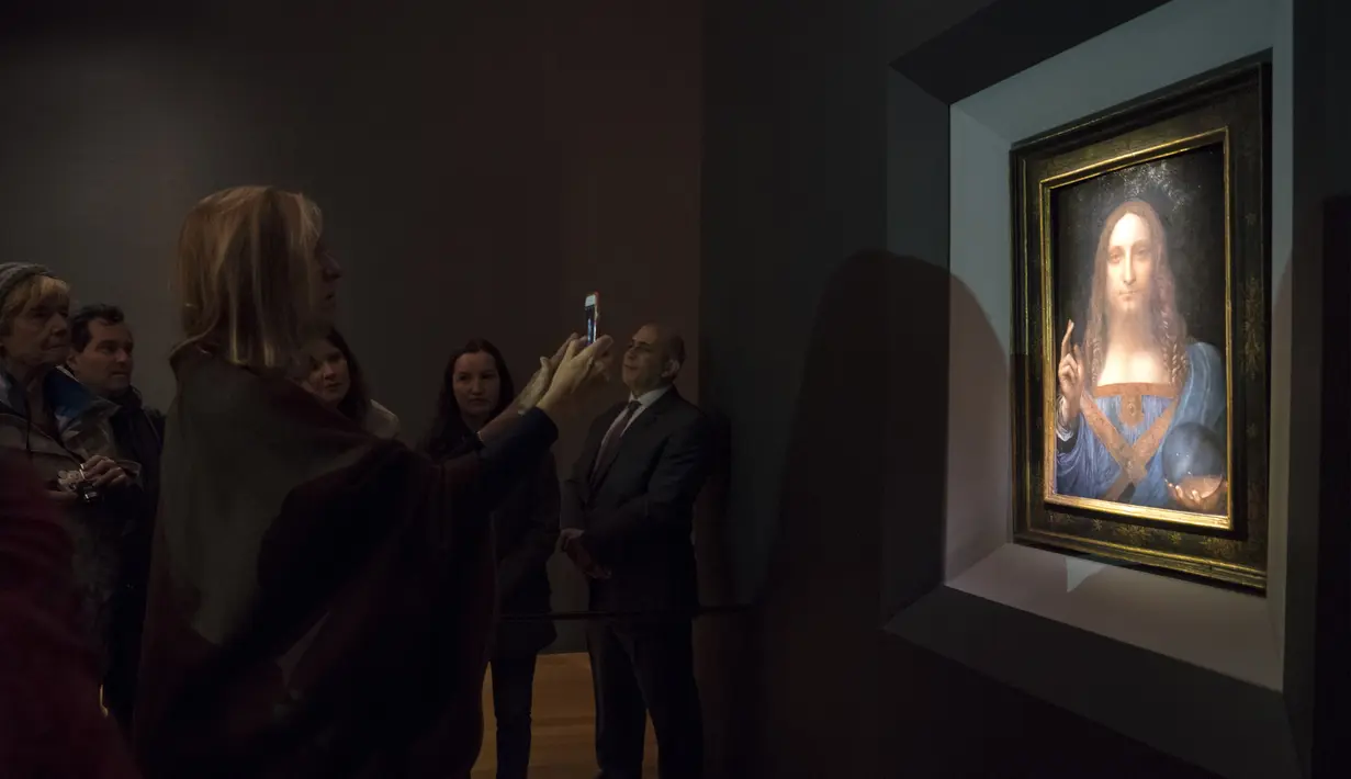 Sejumlah pengunjung melihat lukisan 'Salvator Mundi' karya Leonardo da Vinci di Christie's New York Auction House, New York City (15/11). Lukisan ini terjual seharga US$ 450,3 juta atau setara Rp 6 triliun. (Drew Angerer/Getty Images/AFP)