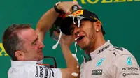Direktur Mercedes, Paddy Lowe menuangkan sampanye ke Lewis Hamilton usai merebut gelar GP F1 di Sirkuit The Americas, Minggu (25/10). Ini merupakan gelar juara dunia ketiga bagi Hamilton setelah sebelumnya diraih pada 2008 dan 2014. (REUTERS/Mike Stone)