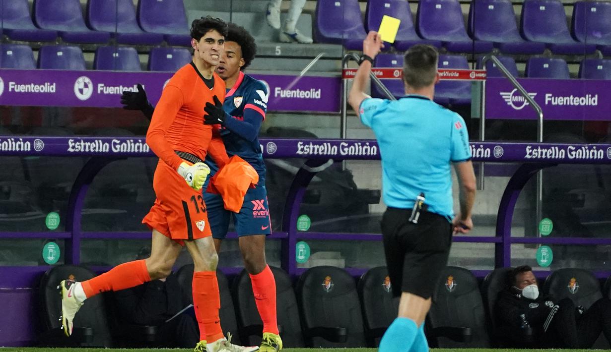 Kiper Sevilla, Yassine Bounou Bono (kiri) menerima kartu kuning dari wasit Adrian Cordero saat menghadapi Real Valladolid dalam laga lanjutan Liga Spanyol 2020/2021 pekan ke-28 di Jose Zorrilla Stadium, Valladolid, Sabtu (20/3/2021). Sevilla bermain imbang 1-1 dengan Valladolid. (AFP/Cesar Manso)