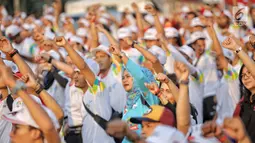 Warga mengikuti gerakan senam sembari menunggu prosesi Torch Relay Asian Games 2018 di Jakarta, Sabtu (18/8). Hari ini merupakan puncak kirab obor Asian Games 2018 dimana api abadi akan berlabuh di Gelora Bung Karno. (Liputan6.com/Faizal Fanani)