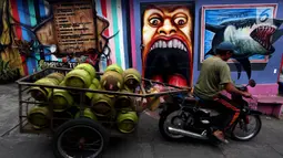 Pekerja membawa tabung gas di Kampung Warna-warni Jodipan dan Kampung Tridi (3D) di pinggir Sungai Brantas, Tumenggungan Ledok, Blimbing, Kota Malang, Jawa Timur (29/7). Kini kampung ini dikreasikan dengan penuh warna. (Liputan6.com/Johan Tallo)
