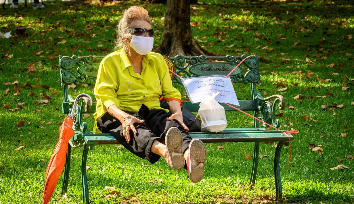 Seorang wanita duduk di bangku yang ditandai untuk menjaga jarak di Taman Lumpini yang dibuka kembali usai pelonggaran beberapa langkah pengendalian karena Corona COVID-19 di Bangkok, Minggu (3/5/2020). Thailand mulai melonggarkan aturan pembatasan pergerakan orang dan pertemuan. (VIVEK PRAKASH/AFP)