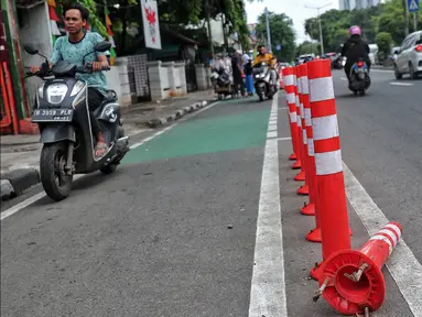 Pengendara bermotor melintas di samping stick cone pembatas jalur sepeda di Kawasan Jalan Penjernihan Jakarta, Sabtu (10/12/2022). Keadaan stick cone untuk pembatas jalur sepeda tersebut terlihat sudah rusak dan tidak terpasang dengan benar. (Liputan6.com/Angga Yuniar)