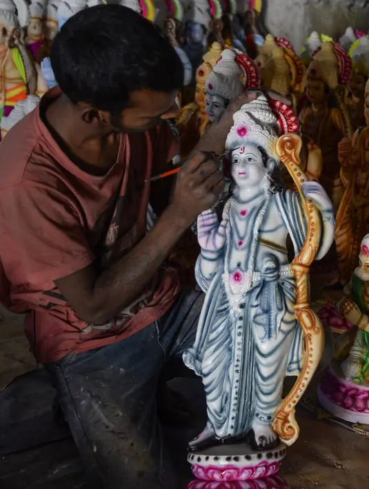 Seorang seniman India memberikan sentuhan terakhir untuk menyelesaikan pembuatan dewa Hindu Rama di sebuah lokakarya di Hyderabad, India (15/3). Para seniman ini membuat patung dewa menjelang festival Rama Navami. (AFP/Noah Seelam)