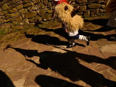 Seorang anak mengenakan kostum dengan latar belakang bayangan peserta karnaval di antara desa Pyrenees Ituren dan Zubieta, Spanyol (29/1). Acara ini merupakan salah satu karnaval paling kuno di Eropa. (AP Photo / Alvaro Barrientos)