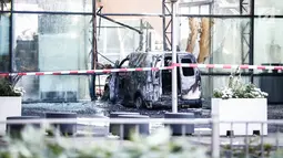 Sebuah mobil van hangus setelah menabrak pintu depan gedung tempat surat kabar ternama Belanda, De Telegraaf di Amsterdam, Selasa (26/6). Polisi menduga, tabrakan itu disengaja tetapi pengemudi minibus berhasil melarikan diri. (KOEN VAN WEEL/ANP/AFP)