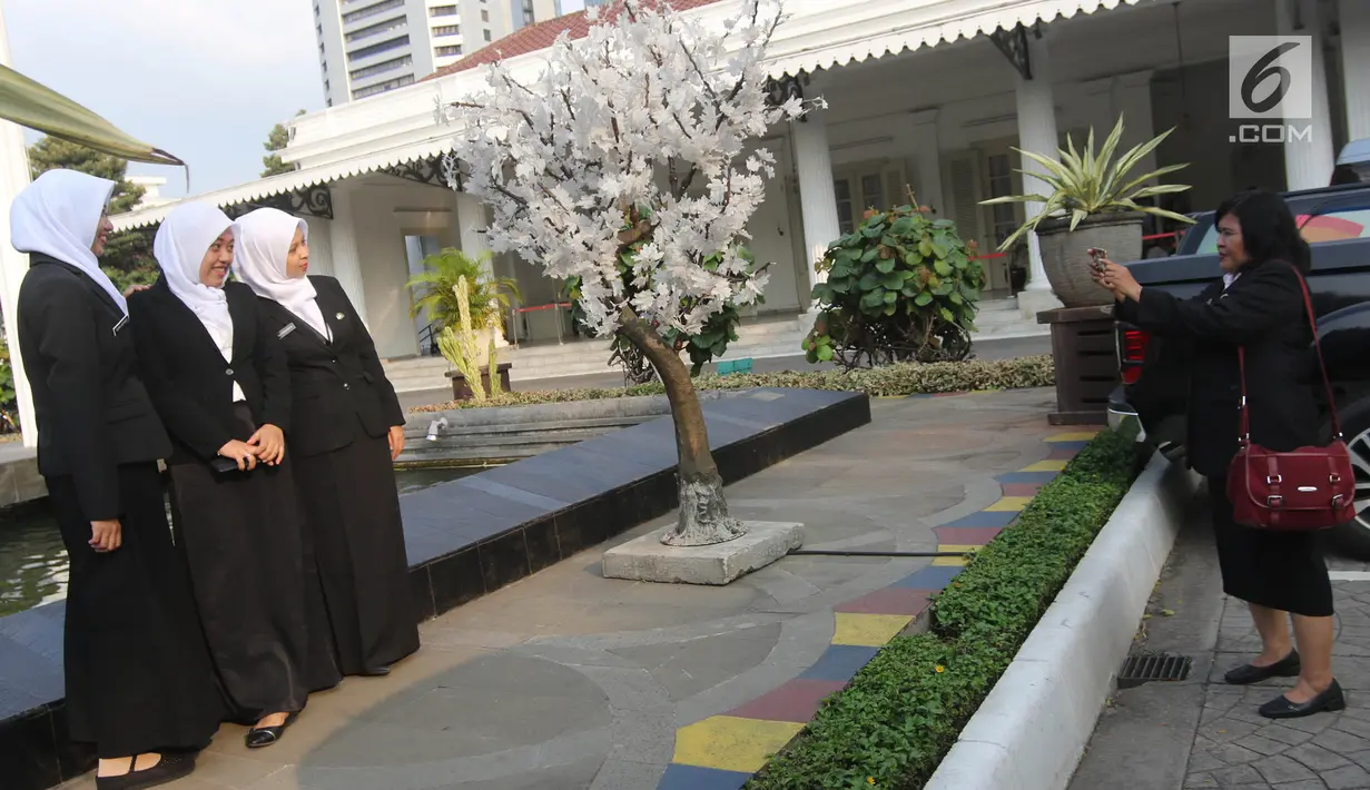 Sejumlah pegawai foto di samping pohon imitasi yang terpasang di halaman Balai Kota DKI Jakarta, Senin (4/6). Sebelumnya, pohon imitasi itu dipasang di trotoar yang ada di Jalan Medan Merdeka Barat, Thamrin hingga Sudirman. (Liputan6.com/Arya Manggala)
