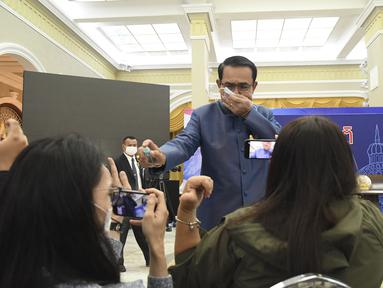 Perdana Menteri (PM) Thailand, Prayuth Chan-ocha menyemprot cairan disinfektan kepada barisan depan wartawan di ruang konferensi pers di Government House di Bangkok, Selasa (9/3/2021). Prayuth merasa terganggu saat wartawan mencecarnya dengan berbagai pertanyaan soal reshuffle kabinet. (AP Photo)