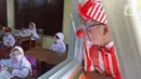 Seniman Aku Badut Indonesia (ABI) melihat siswa belajar di SDN 03 Citayam, Kabupaten Bogor, Jawa Barat, Senin (6/9/2021). Aksi tersebut tentang protokol kesehatan serta membagikan masker kepada anak-anak sekolah yang menggelar Pembelajaran Tatap Muka (PTM). (Liputan6.com/Herman Zakharia)