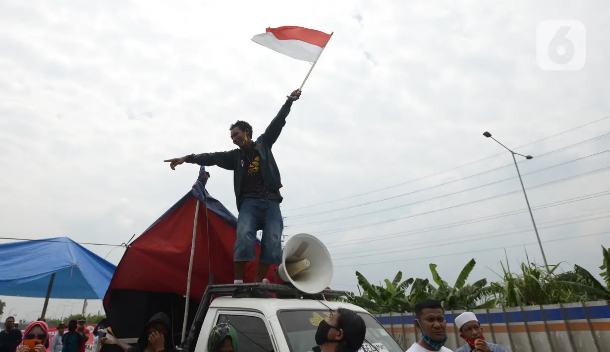 Warga Kampung Sawah melakukan aksi dengan menutup akses jalan Cakung Cilincing, Jakarta, Rabu (18/11/2020). Aksi tutup jalan ini merupakan sebagai bentuk protes warga atas hak tanahnya yang terkena proyek pembangunan jalan tol Cakung Cilincing (Cacing)-Cibitung. (merdeka.com/Imam Buhori)