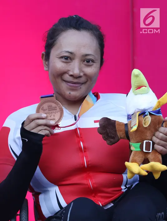 Atlet ParaCycling, Ni Kadek Karyadewi memperlihatkan medali perunggu nomor Womens H2-4 Individual Time Trial Road Race Asian Para Games 2018 usai prosesi pengalungan medali di Sirkuit Sentul, Bogor, Senin (8/10). (Liputan6.com/Helmi Fithriansyah)