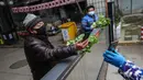 Seorang penduduk membayar sayur-sayuran di atas gerbang di Wuhan di provinsi Hubei tengah China (3/3/2020). Hingga saat ini, jumlah total kasus virus corona secara global dilaporkan mencapai 89.770 kasus yang tersebar di sekitar 70 negara termasuk Indonesia. (AFP/STR)