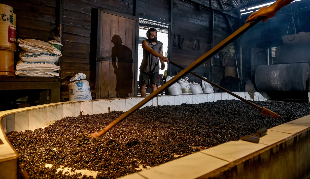 Para pekerja menyebarkan biji kopi robusta setelah disangrai secara tradisional di sebuah pabrik biji kopi kecil di Banda Aceh (14/11/2020). (AFP/Chaideer Mahyuddin)