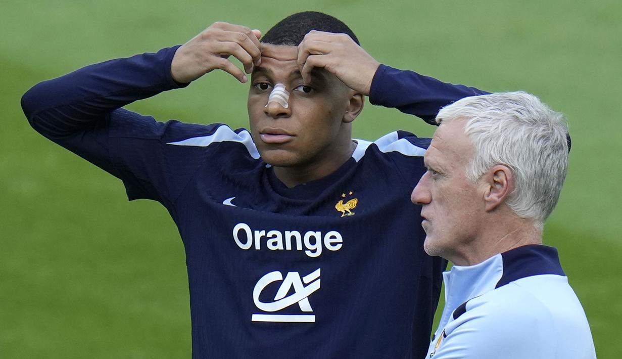 Pemain Prancis, Kylian Mbappe (kiri) di samping pelatih Didier Deschamps saat berlatih jelang laga Grup D melawan Belanda di Home Deluxe Arena Stadium, Paderborn, Jerman, Rabu (19/06/2024) waktu setempat. Mbappe terlihat menggunakan perban hidung setelah mengalami cedera patah tulang hidung pada laga Grup D Prancis melawan Austria Selasa (18/06/2024) WIB lalu. (AP Photo/Hassan Ammar)