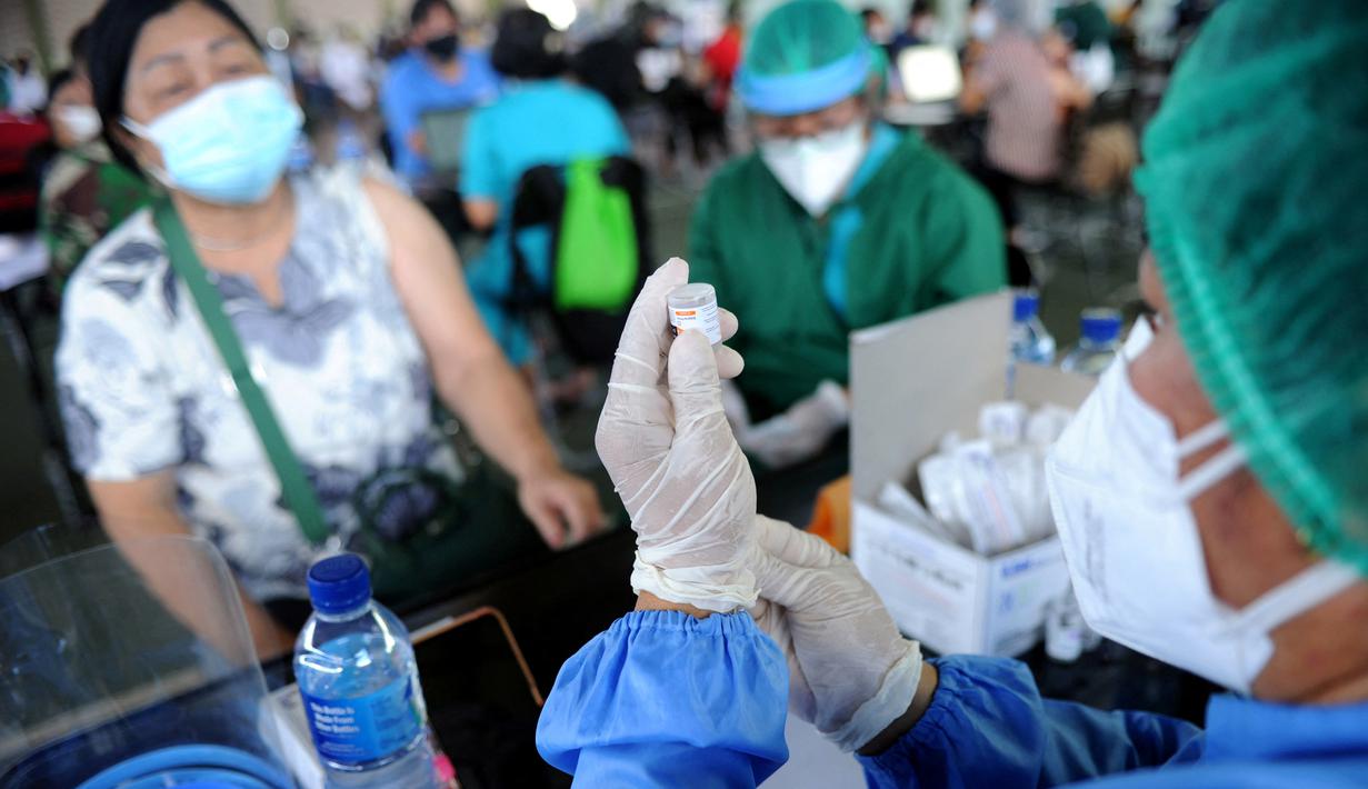 Seorang petugas kesehatan (kanan) bersiap untuk memberikan vaksin virus corona COVID-19 AstraZeneca di klinik vaksinasi massal darurat di Denpasar, Bali, Selasa (6/7/2021). Indonesia tengah memerangi gelombang infeksi baru yang belum pernah terjadi sebelumnya. (SONNY TUMBELAKA/AFP)