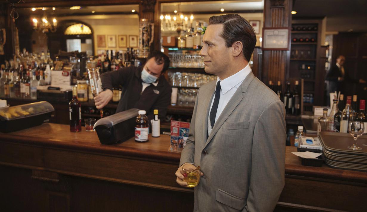 Patung lilin aktor John Hamm dengan memegang minuman berdiri dekat meja bar di Peter Luger Steakhouse, New York, Jumat (26/2/2021). Patung yang dipinjam dari Madame Tussauds itu membantu mengisi meja kosong selama pelonggaran pembatasan aturan COVID-19 makan di dalam ruangan.  (AP Photo/Kevin Hagen)