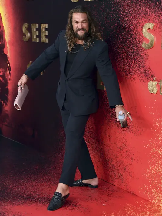 Jason Momoa berpose saat menghadiri pemutaran perdana musim ketiga film "See," di DGA Theater di Los Angeles (23/8/2022). Jason Momoa membawa tas kecil berwarna pink serta botol minuman. (Jordan Strauss/Invision/AP)