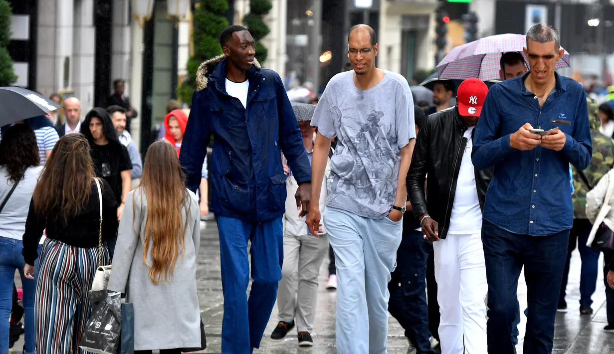 Abdramane Dembel dari Pantai Gading (2,35 meter), Brahim Takioullah dari Prancis (2,46 meter) dan Arshavir Grigoryan dari Armenia (2,33 meter) berjalan di tengah keramaian ketika orang tertinggi sedunia bertemu di Paris, 1 Juni 2018. (AFP/GERARD JULIEN)