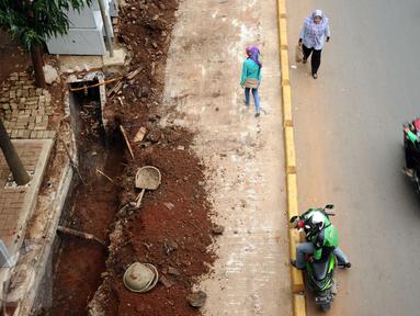 Warga melintas di sisi proyek pembangunan trotoar Jalan Raya Kalibata, Jakarta, Rabu (2/11). Pembangunan penataan trotoar di kawasan Jalan Raya Kalibata, Jakarta Selatan baru mencapai 15 persen. (Liputan6.com/Helmi Fithriansyah)