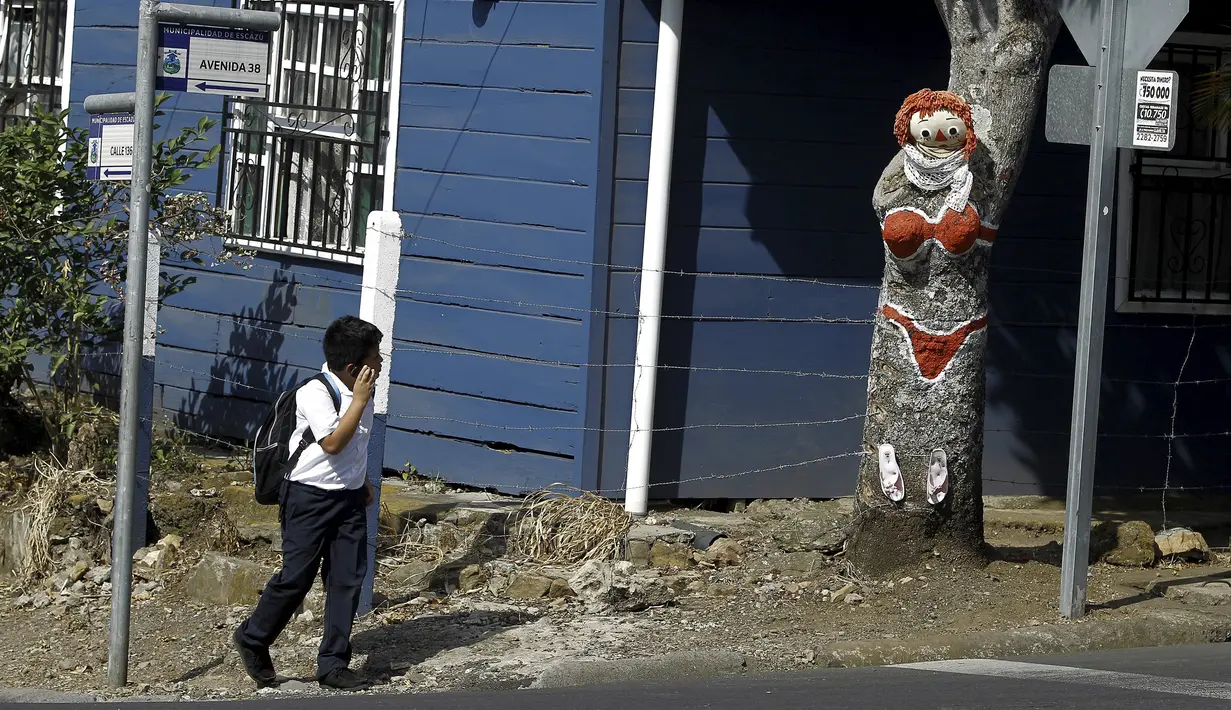 Seorang anak melihat pohon mangga yang dilukis oleh Gonzalo Sanchez di sudut jalan di lingkungan Escazu, Kosta Rika, Selasa (1/3). Lukisan bernama "The Woman in Red Bikini" itu menirukan sosok wanita yang mengenakan bikini. (REUTERS/Juan Carlos Ulate)