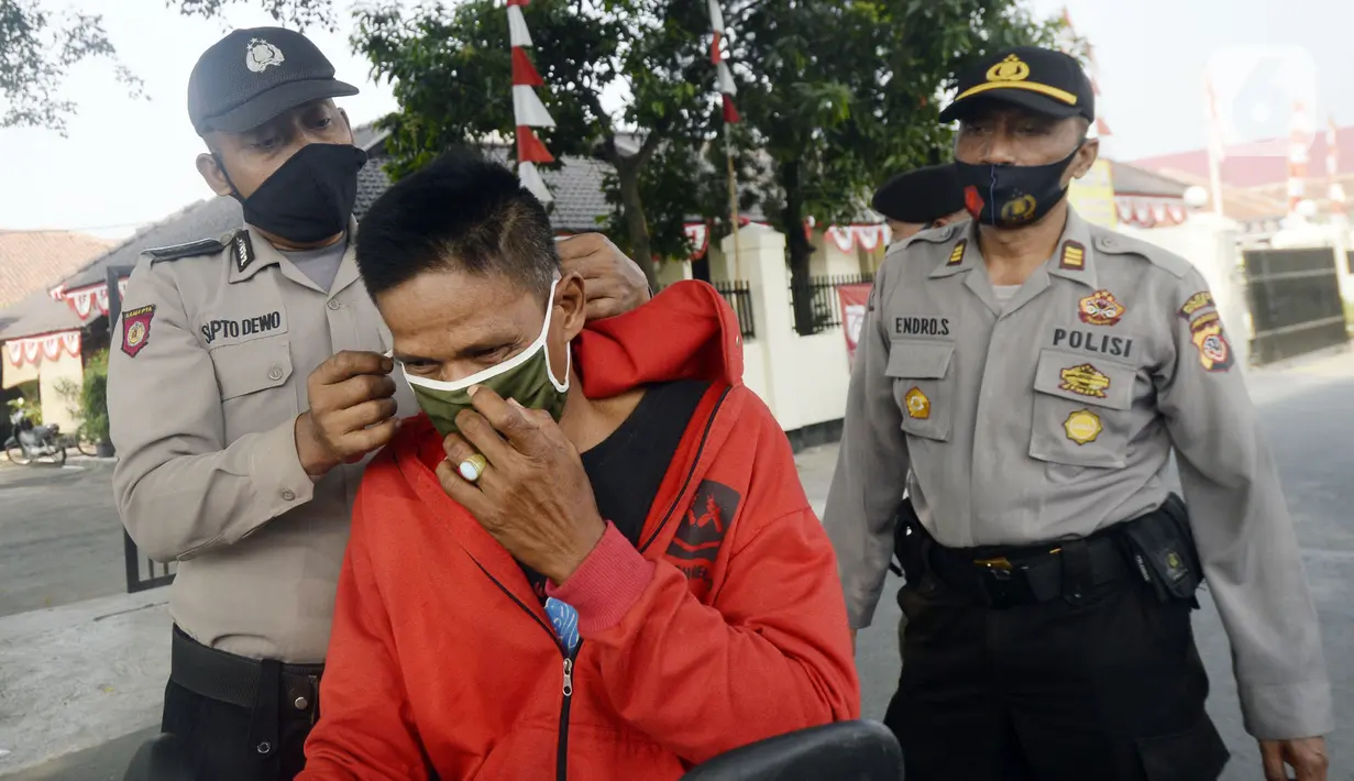 Anggota polisi dari Polsek Parung membantu memasangkan masker kepada pengendara sepeda motor di depan Polsek Parung, Kabupaten Bogor, Jawa Barat, Rabu (2/9/2020). Pembagian masker gratis ini untuk mengajak masyarakat hidup sehat dan mencegah penular COVID-19. (merdeka.com/Dwi Narwoko)