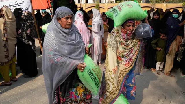 Perempuan dengan sekarung tepung terigu gratis di tempat distribusi sembako Ramadhan di Lahore, Pakistan [File: KM Chaudary/AP]