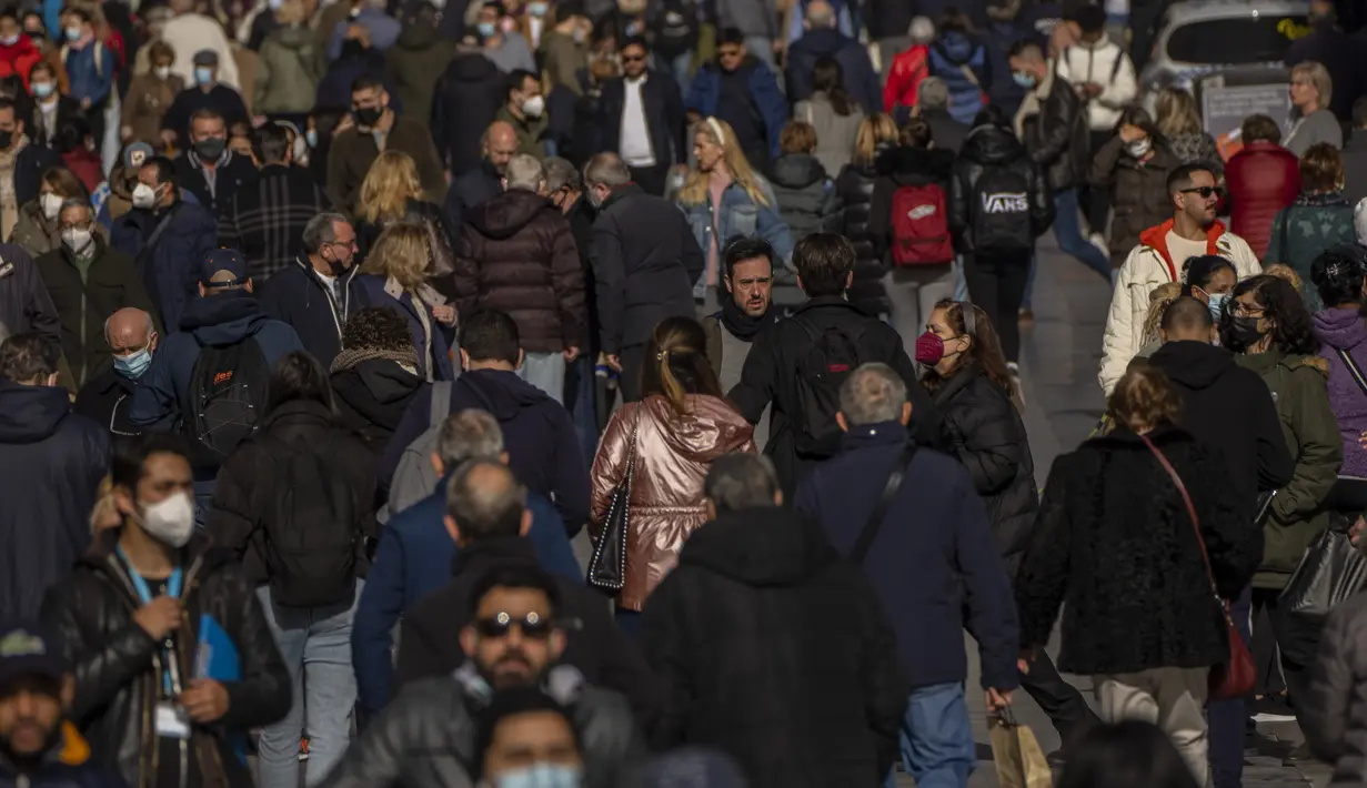 Orang-orang, beberapa dari mereka tanpa masker, berjalan di sepanjang jalan di pusat kota Madrid, Kamis (10//2/2022). Warga Spanyol untuk pertama kalinya dalam hampir dua bulan diperbolehkan tidak menggunakan masker di luar ruangan setelah peraturan terkait hal itu dicabut. (AP Photo/Manu Fernandez)