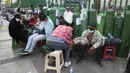 Orang-orang duduk di dekat tabung oksigen kosong mereka saat menunggu toko isi ulang dibuka di lingkungan San Juan de Lurigancho di Lima, Peru, Senin (22/2/2021). Mereka antre tabung oksigen untuk anggota keluarga yang membutuhkan di tengah gelombang kedua pandemi Covid-19. (AP Photo/Martin Mejia)