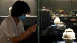 Pengunjung memotret benda yang dipajang dalam pameran keramik di Zhengzhou, Provinsi Henan, China, 25 Agustus 2020. Pameran keramik tersebut dimulai di Zhengzhou pada Selasa (25/8) dengan menampilkan 100 lebih benda dari zaman kuno yang ditemukan di sepanjang cekungan Sungai Kuning. (Xinhua/Li An)
